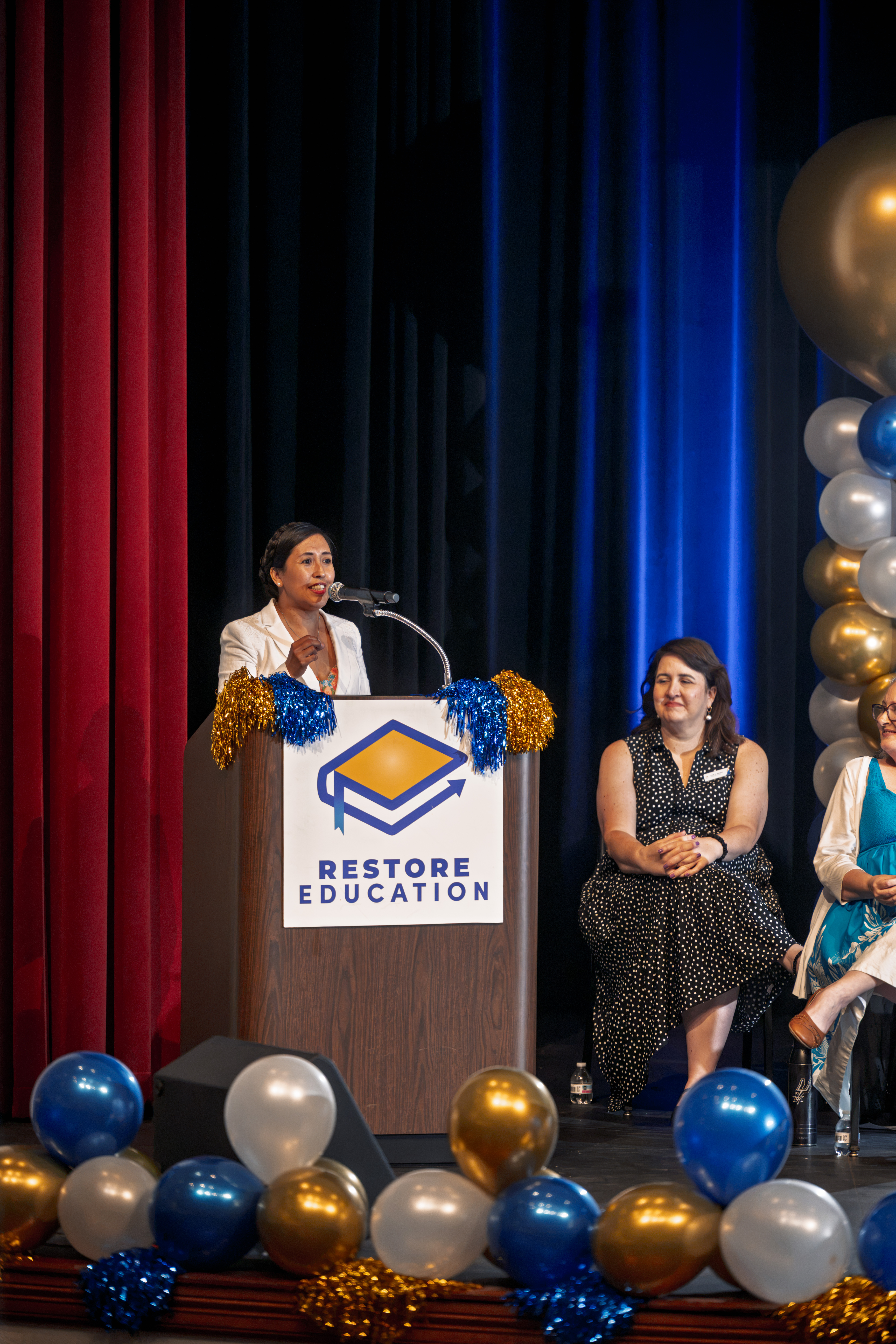 A speaker addresses the audience from the Restore Education podium