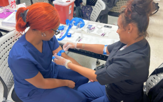 Two medical assistant students in scrubs practicing a phlebotomy blood draw during hands-on training